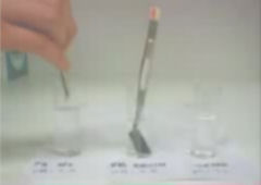 Still from the movie showing base, water and acid solutions which influence adhesion of the electrolyte brushes.